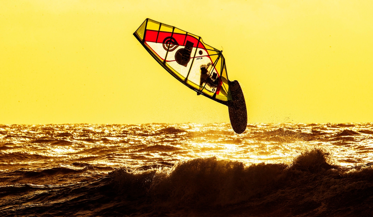 Westerland, Sylt, PWA Windsurf World Cup. Windsurfer springt über eine Welle im Sonnenuntergang.